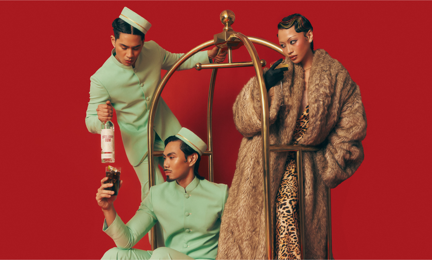 Two models in theatrical outfits including leopard print posing with Hotel Lobby Rum on red background