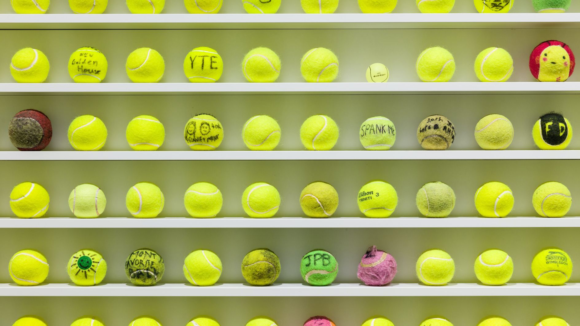 Grid of yellow-green tennis balls with various stamps and markings