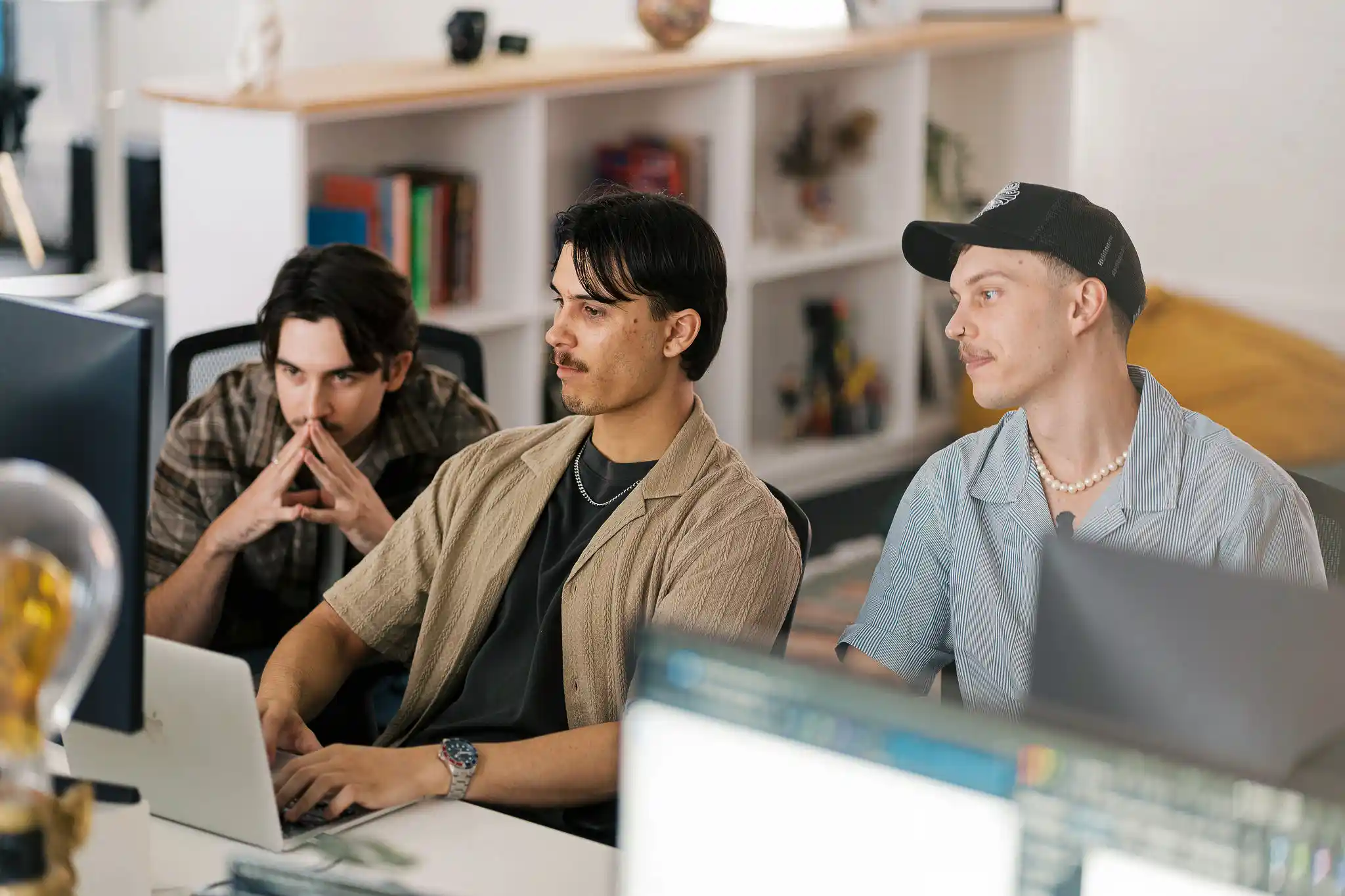Two Start team members working together at a computer workstation, one pointing at the screen, in a modern office with bookshelves